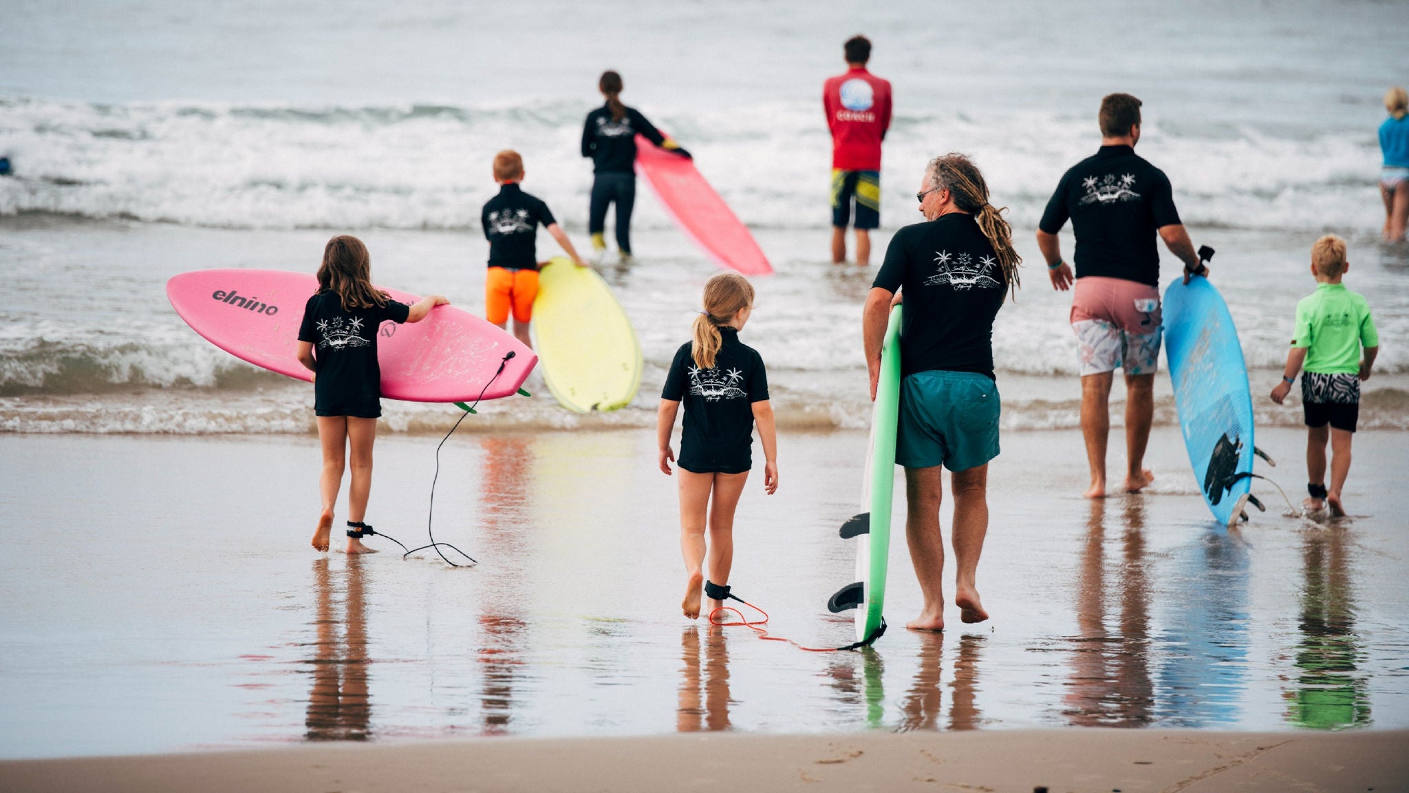 Adults and children entering the surf as part of SalTy Souls community program.