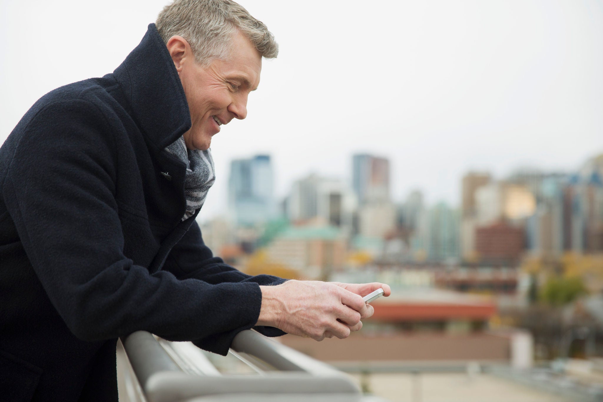 16 Oct 2012 --- Profile of businessman texting on cell phone outdoors. --- Image by © Hero Images/Corbis