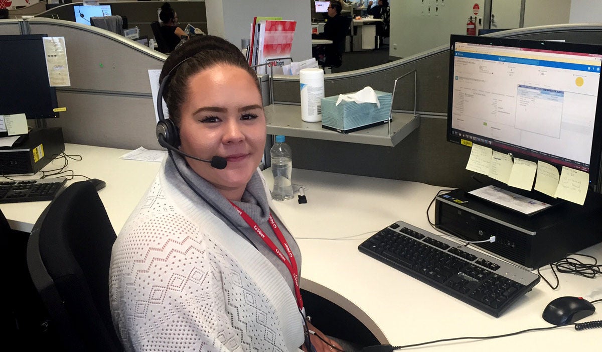 Woman sitting in an office with a headset with a mic on