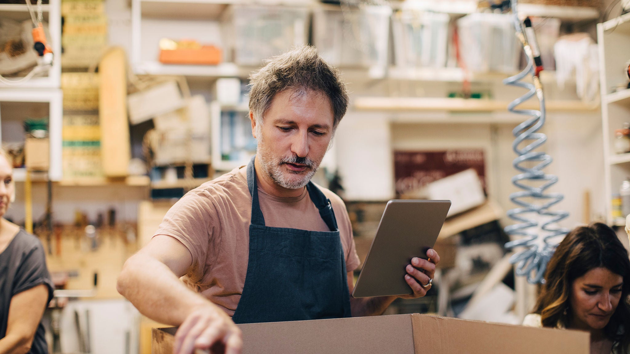 photo-man-wearing-apron-holding-tablet-packing-box-in-shop