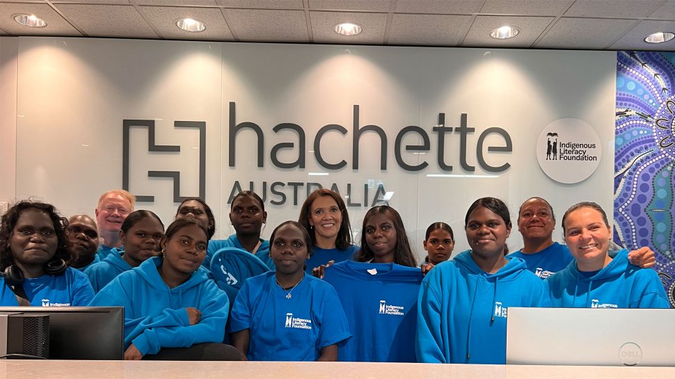 A group of young First Nations girls standing in from of the Hachette signage.