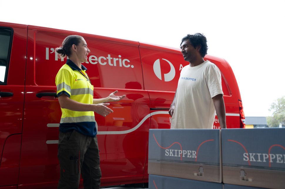Skipper founder speaking with an Australia Post team member next to an electric delivery van and Skipper parcels.