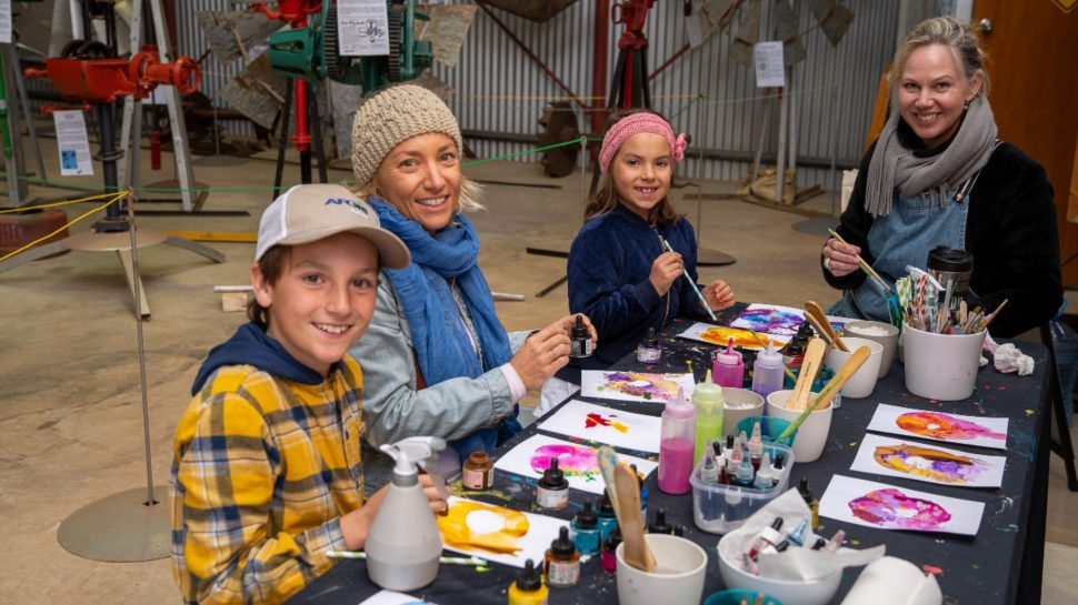 Two women and a young boy and girl sitting at a table, painting. 